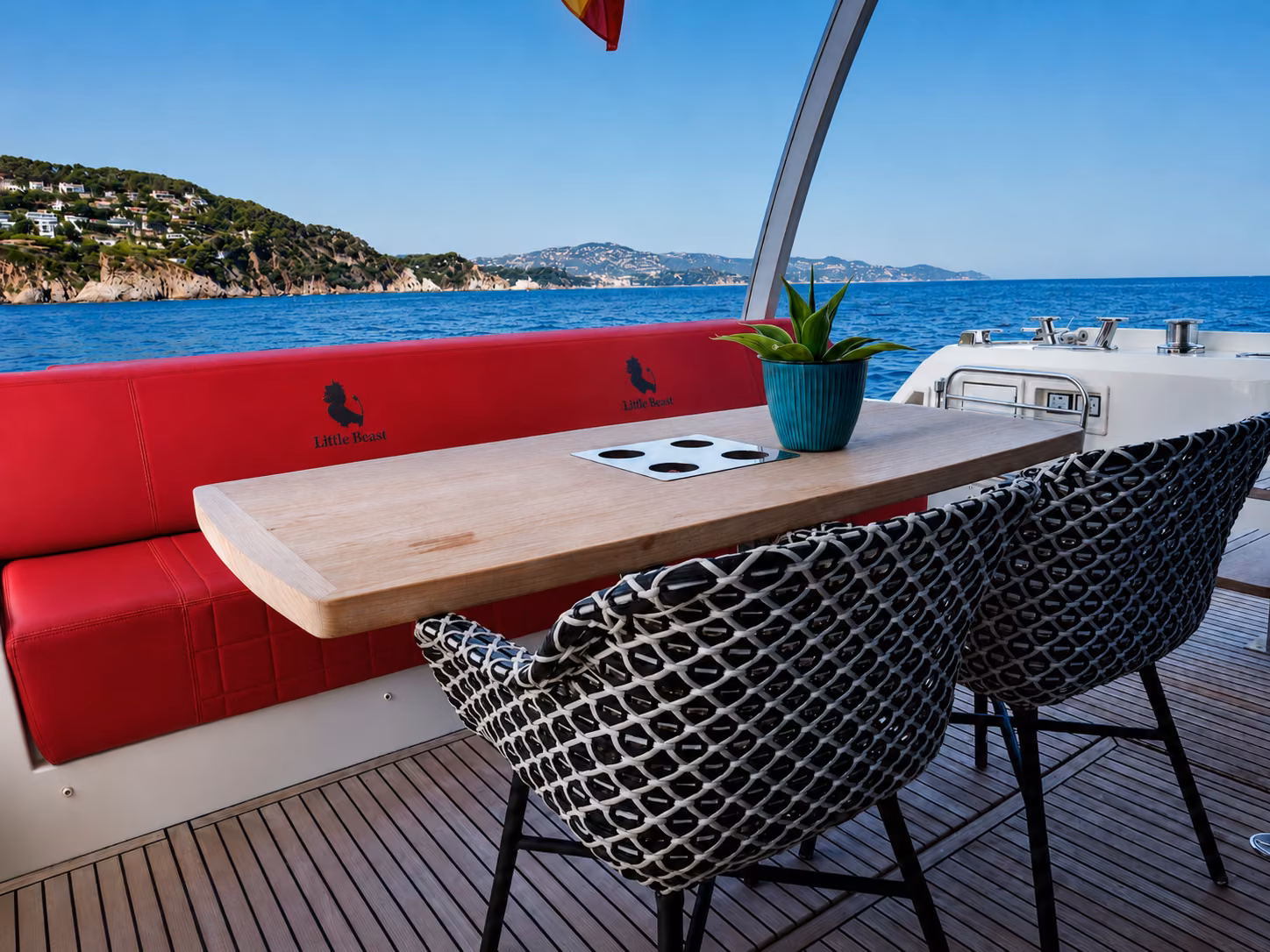 Zona exterior de un yate con mesa, asientos y vistas a la costa