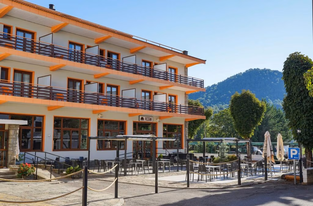 Fachada y terraza exterior de un hotel de montaña rodeado de arbolado
